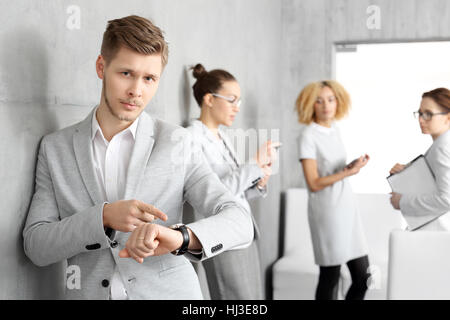 Zeit ist Geld. Während des Wartens auf ein Vorstellungsgespräch. Junger Mann seine Uhr stehen auf dem Flur außerhalb des Büros zu überprüfen. Stockfoto