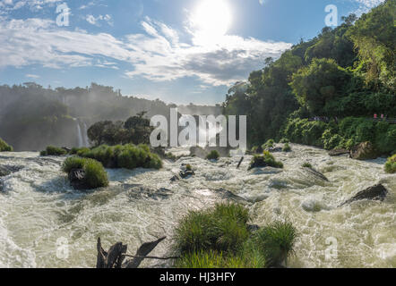 Cataratas Wasserfälle Ansicht von unten mit einigen Felsen bedeckt von Grass vor dem Wasserfall und strahlend blauen Himmel als Hintergrund Stockfoto