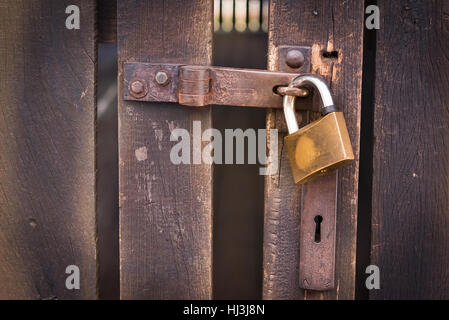 Nahaufnahme eines Vorhängeschlosses mit einem alten Metall Hasp und Grundnahrungsmittel auf einer alten Holztür Stockfoto