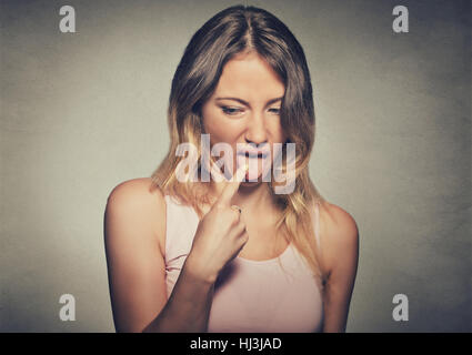 Closeup Portrait junge Frau, verärgert, frustriert stecken ihre Finger in der Kehle zeigt, sie ist über dem Kopf zusammenschlagen isoliert auf graue Wand Rücken satt Stockfoto