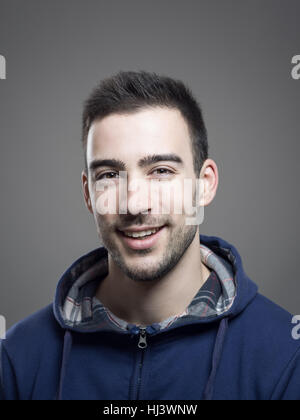 Fröhliche positive junge Stoppeln Mann mit blauen Kapuzen Shirt Blick in die Kamera Stockfoto