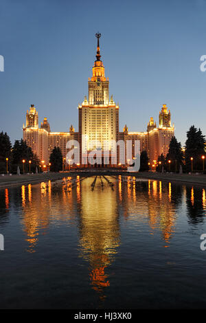 Moskauer Staatsuniversität (MGU) in der Dämmerung mit goldenen Reflexion in einem Wasserbecken. Moskau bei Nacht, Russland. Stockfoto