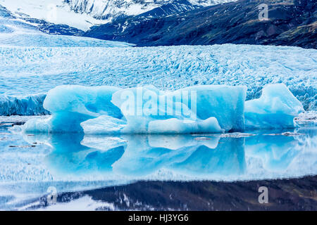 Eisberge entlang der Ufer der Jökulsárlón Gletscherlagune Verlauf einer blauen bewölkten Tag bewegungslos während umrahmt von einer kalten Ozeanwasser. Stockfoto