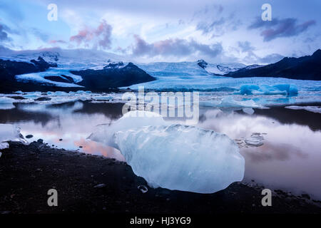 Eisberge entlang der Ufer der Jökulsárlón Gletscherlagune Verlauf einer blauen bewölkten Tag bewegungslos während umrahmt von einer kalten Ozeanwasser. Stockfoto