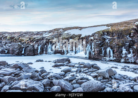 Ein gefrorenen Fluss im Hochland von Island eingerahmt von Pastell Himmel und zerklüftete Gelände bietet landschaftlich Inbegriff der gefrorenen Wildnis. Stockfoto