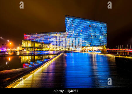 Harpa Konzertsaal in Island in der Nacht leuchtet in verschiedenen Farben, Nachdenken über einen Pool an der Vorderseite des Gebäudes. Stockfoto