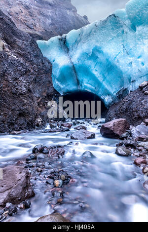 Eine Eishöhle in Island unter einem Gletscher gebildet wird schmelzen und bilden einen Fluss durch den Mund der Höhle muhen. Stockfoto