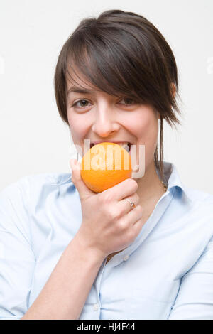 Junge Frau, die eine Orange Essen Stockfoto