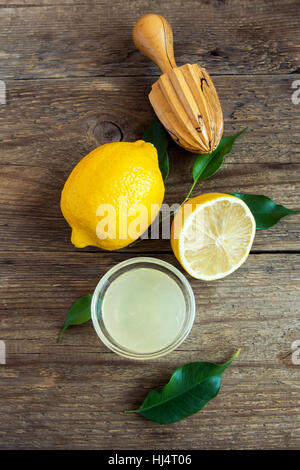 Frischer Zitronensaft in kleinen Schüssel und Zitronen auf rustikalen hölzernen Hintergrund mit textfreiraum - gesunde Zutat zum Kochen und backen Stockfoto