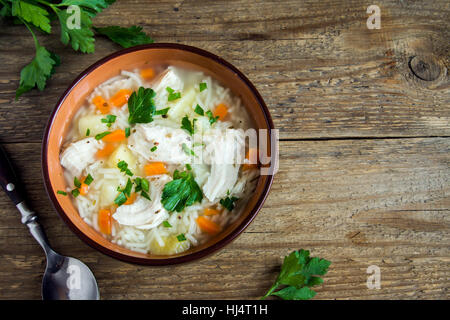 Hühnersuppe mit Nudeln und Gemüse in Schüssel über rustikalen hölzernen Hintergrund - hausgemachte gesunde Mahlzeit Stockfoto