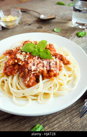 Spaghetti Bolognese Nudeln mit Tomatensauce und Hackfleisch / Faschiertes, geriebenem Parmesan und frischem Basilikum - gesunde italienische Pasta aus Eigenproduktion auf rustikal aus Holz Stockfoto