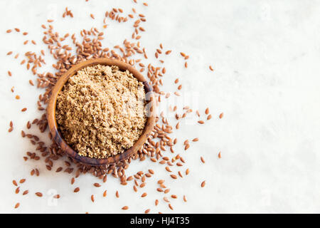 Schüssel mit zerquetschten Leinsamen (Boden Leinsamen) auf weißen Steintisch - gesunde Bio Vegan vegetarisch Lebensmittelzutat Stockfoto