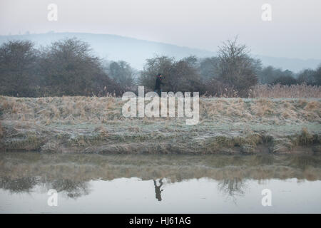 Eine Person, die Spaziergänge entlang der Bahn neben dem Fluss Arun in Arundel, West Sussex, UK an einem kalten und frostigen Morgen. Stockfoto