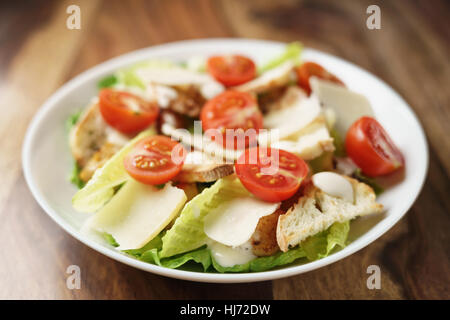 frische hausgemachte Caesar Salat mit Hühnchen und Kirschtomaten auf Holztisch Stockfoto