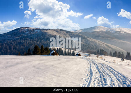 Heuhaufen in der Nähe der Weg durch landwirtschaftlichen Bereich auf verschneiten Hügel am nebligen Morgen in Winterbergen Stockfoto