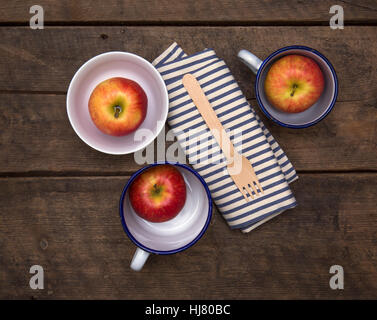 Äpfel in Schalen mit Gabel und Serviette auf einem rustikalen Holztisch Stockfoto