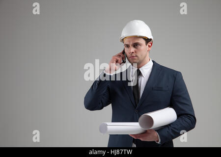 Porträt eines Geschäftsmannes in weißen Helm auf grauem Hintergrund Stockfoto