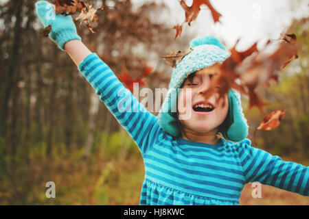 Mädchen werfen Herbst Blätter in der Luft Stockfoto