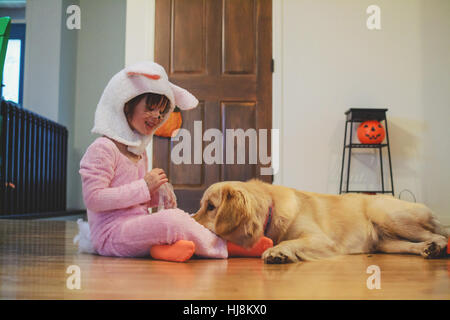 Mädchen im Bunny-Kostüm mit Golden Retriever Hund spielen Stockfoto