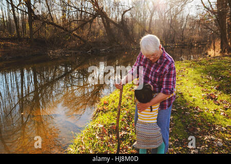 Mädchen umarmt ihre Großmutter im Wald an einem Fluss Stockfoto