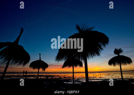 Silhouette von zwei Personen und Sonnenschirme am Strand Los Lances, Tarifa, Cadiz, Andaulcia, Spanien Stockfoto