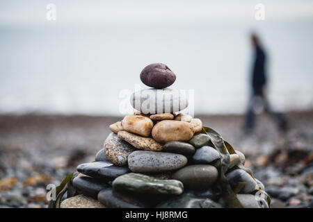 Defokussierten Person Vorbeigehen einen Stapel von Kiesel am Strand, Irland Stockfoto