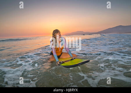 Frau sitzt auf Surfbrett, Los Lances Strand, Tarifa, Cádiz, Andalusien, Spanien Stockfoto