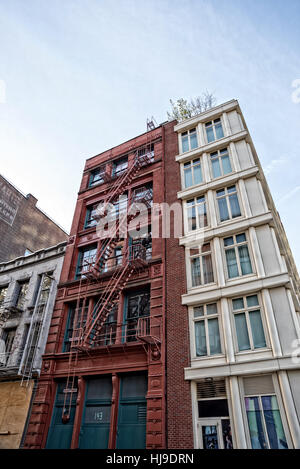 New York City, Manhattan, Soho, Houston Street.  Looking Up an zwei Gebäuden - alte Cast Iron Red One und Beige neue One. Stockfoto