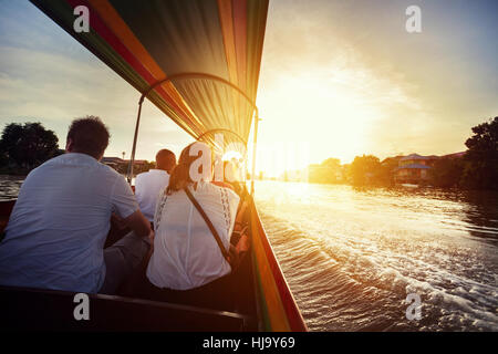 Touristen sitzen im Longtail-Boot Kreuzfahrt durch den Fluss Chao Phraya in antiken Stadt Ayutthaya bei Sonnenuntergang, Thailand Stockfoto