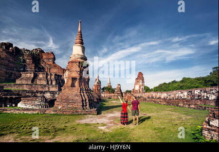 Junges Paar in roter Kleidung mit Fotokamera, Blick auf alten zerstörten Wat Mahathat in Ayutthaya, Thailand Stockfoto