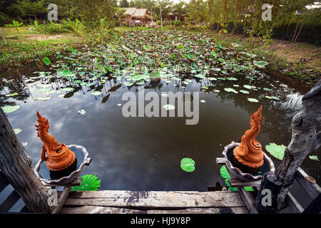 Schönen Teich mit Lotus und Drachen Statuen in Sukhothai Resort, Thailand Stockfoto