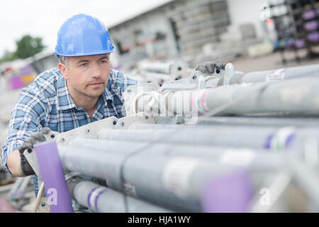 Arbeiter, die Stapel von Gerüstrohren schieben Stockfoto