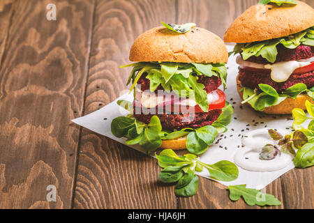 Vegetarische Burger, rote Beete, Tomaten, Feldsalat und Rucola auf hölzernen Hintergrund gemacht Stockfoto