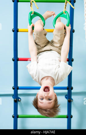 Kid Boy auf die Gymnastik Ringe in der Turnstunde Stockfoto