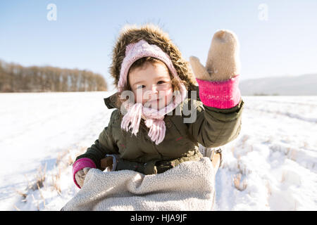 Niedliche kleine Mädchen draußen in der Natur Winter auf Schlitten sitzend Stockfoto