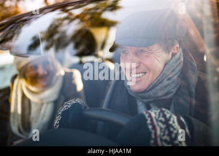Älteres Paar in Winterkleidung Autofahren Stockfoto
