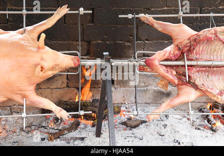 zwei Schweine, die langsam weiter kochen Stahl Spieß in dem riesigen Kamin Stockfoto