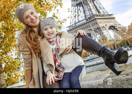 Herbst Kurzurlaube in Paris mit der Familie. glückliche Mutter und Tochter Reisende am Ufer in der Nähe von Eiffel Turm in Paris, Frankreich auf der Brüstung sitzen Stockfoto