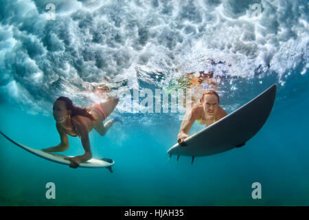 Gruppe von aktiven Mädchen in Aktion. Frauen der Surfer mit Surfbrett Tauchen unter Wasser unter brechende Welle. Wassersport, Extreme Surfen