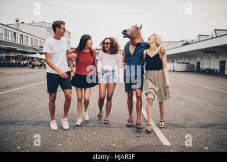 Voller Länge Schuss multirassische junge Freunde Spaß zusammen auf der Straße. Gruppe junger Männer und Frauen gehen im Freien, mit einem Mann mit h Stockfoto