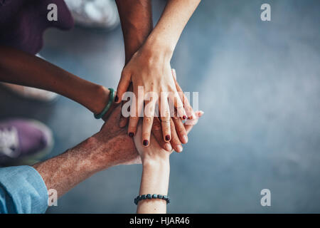 Multiethnische Gruppe von jungen Leuten, die ihre Hände übereinander. Schließen Sie herauf Bild der jungen Studenten, die einen Stapel von Hand machen. Stockfoto