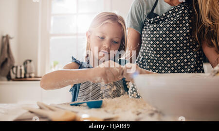 Niedliche kleine Mädchen vorbereitet Teig in Küche mit ihrer Mutter. Junges Mädchen Kochen lernen. Stockfoto