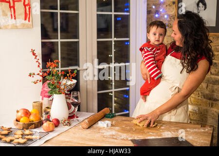 Reife Frau vorbereiten Weihnachtsplätzchen mit Baby Sohn am Küchentisch Stockfoto