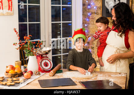 Reife Frau vorbereiten Weihnachtsplätzchen mit Söhnen am Küchentisch Stockfoto