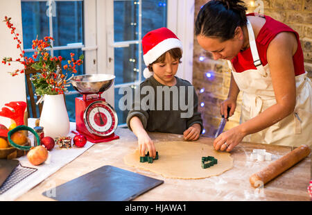 Reife Frau vorbereiten Weihnachtsplätzchen mit Sohn am Küchentisch Stockfoto