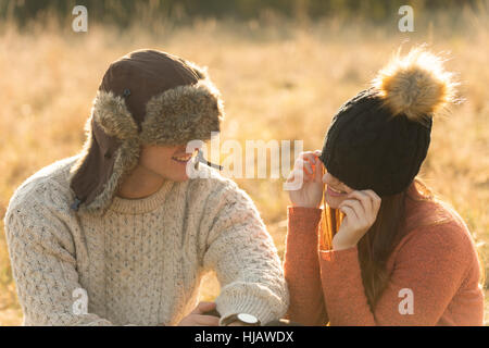 Junges Paar sitzt in ländlicher Umgebung, warme Hüte tragen Stockfoto