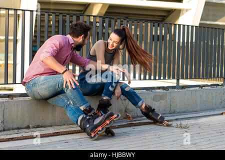 Paar auf Rollerblades sitzt. Stockfoto