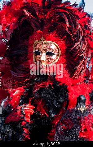 Teilnehmer in bunten roten Kostüm und Maske im traditionellen berühmten Karneval in Venedig, Italien. Stockfoto