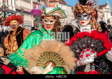 Zwei junge Frauen tragen bunte Kleider und Masken bei traditionellen berühmten Karneval legen jedes Jahr in Venedig. Stockfoto