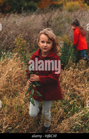 Porträt von Mädchen und ihre Schwester Kommissionierung Wildblumen im Feld Stockfoto